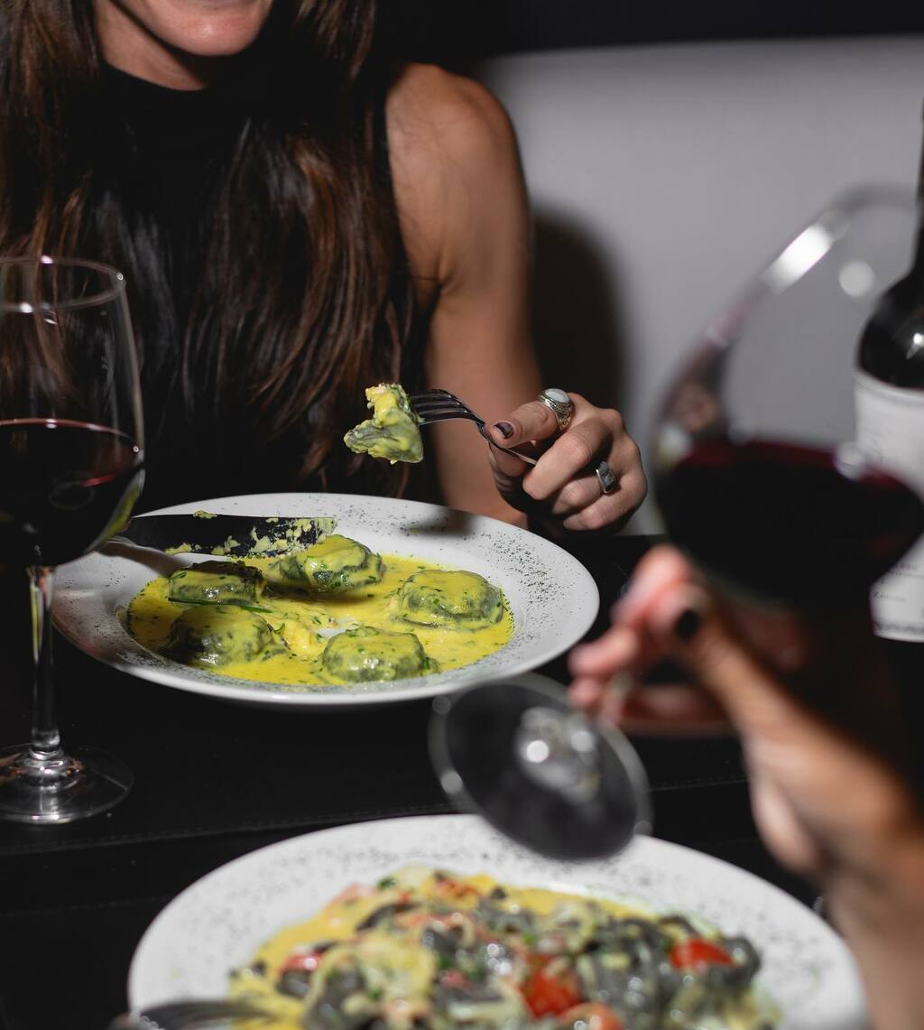 mujer comiendo sorrentinos de espinaca con salsa